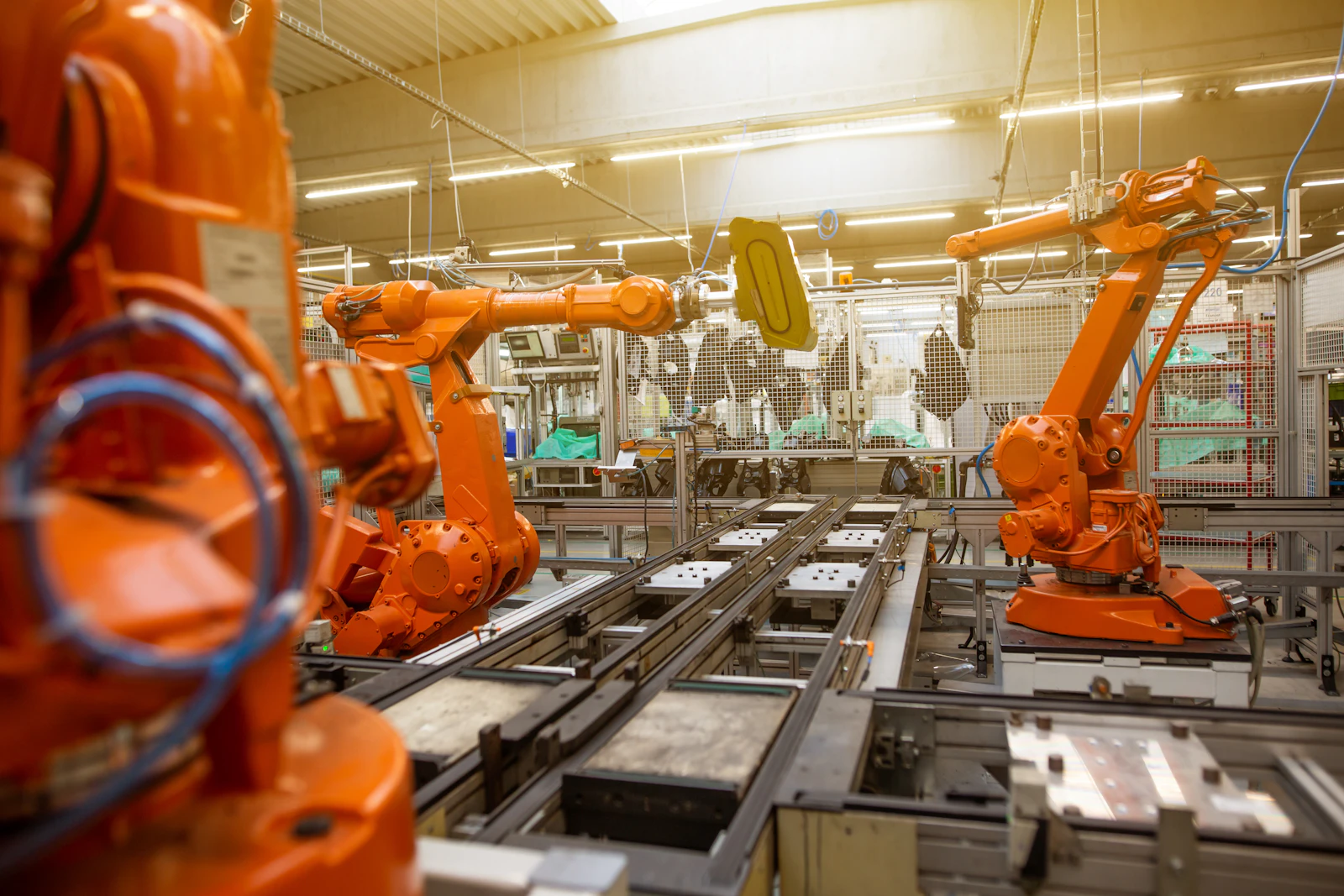 Orange industrial robots positioned along an automotive assembly line.